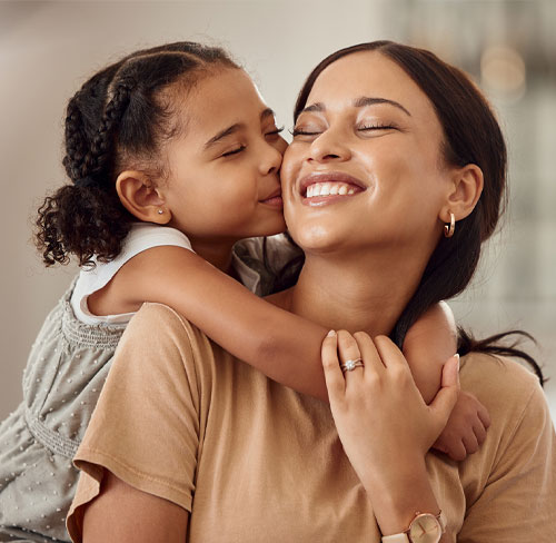 Young girl hugging and kissing smiling mother during Mother's Day Out pickup