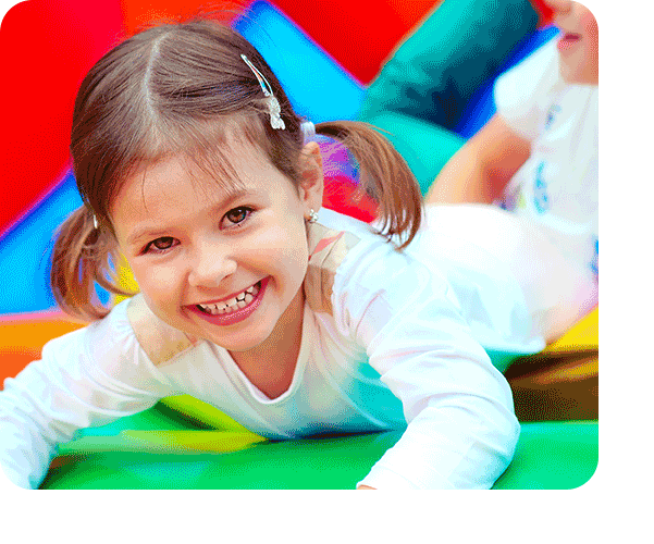 Smiling preschool girl climbing on colorful soft play mats during active indoor play